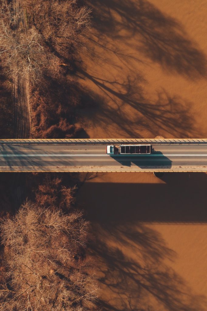 Aerial view of semi-trailer truck crossing the bridge over river, directly above